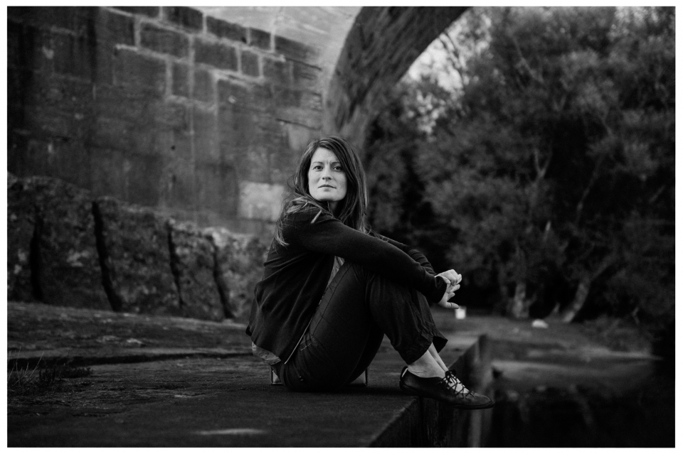 Frau sitzt nachdenklich unter Brücke, Bäume im Hintergrund, schwarz-weiß, ruhige Atmosphäre, © Klaus Gruber | dolphin photography