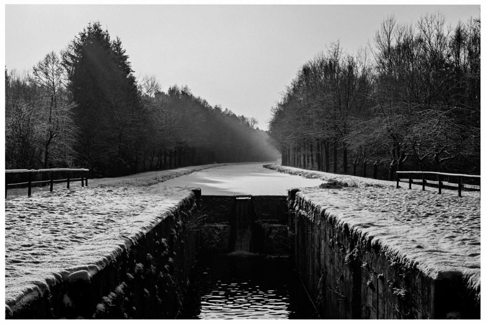 Verschneite Kanallandschaft mit Schleuse, gefrorenem Wasser und schneebedeckten Bäumen, © Klaus Gruber | dolphin photography