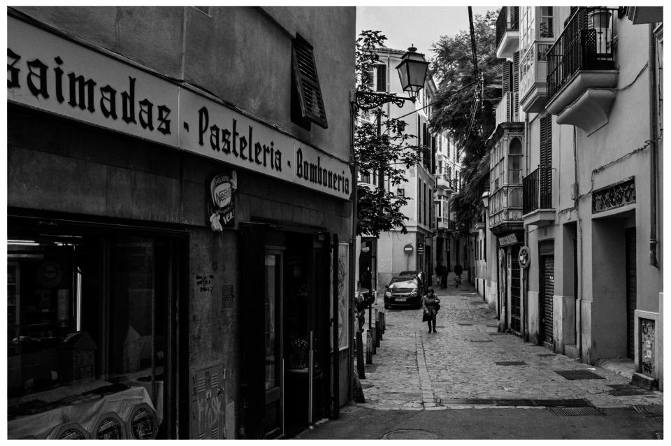 Schwarzweißfoto einer kopfsteingepflasterten Straße mit Geschäften und Balkonen in einer Stadt, © Klaus Gruber | Fotograf Fürth