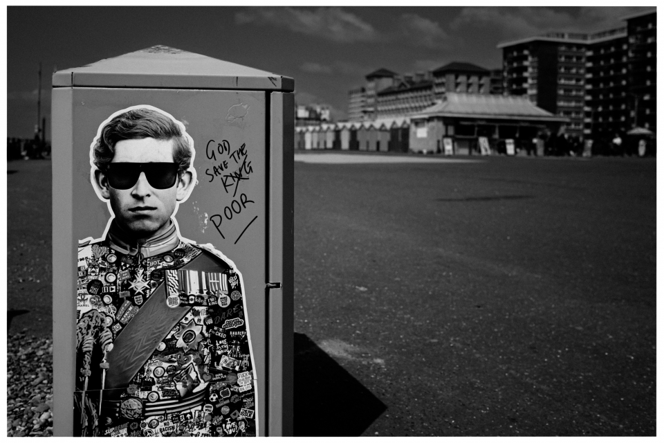 Stromkasten mit Graffiti einer uniformierten Figur, handschriftliche Worte, Gebäude im Hintergrund, © Klaus Gruber | Fotograf Fürth