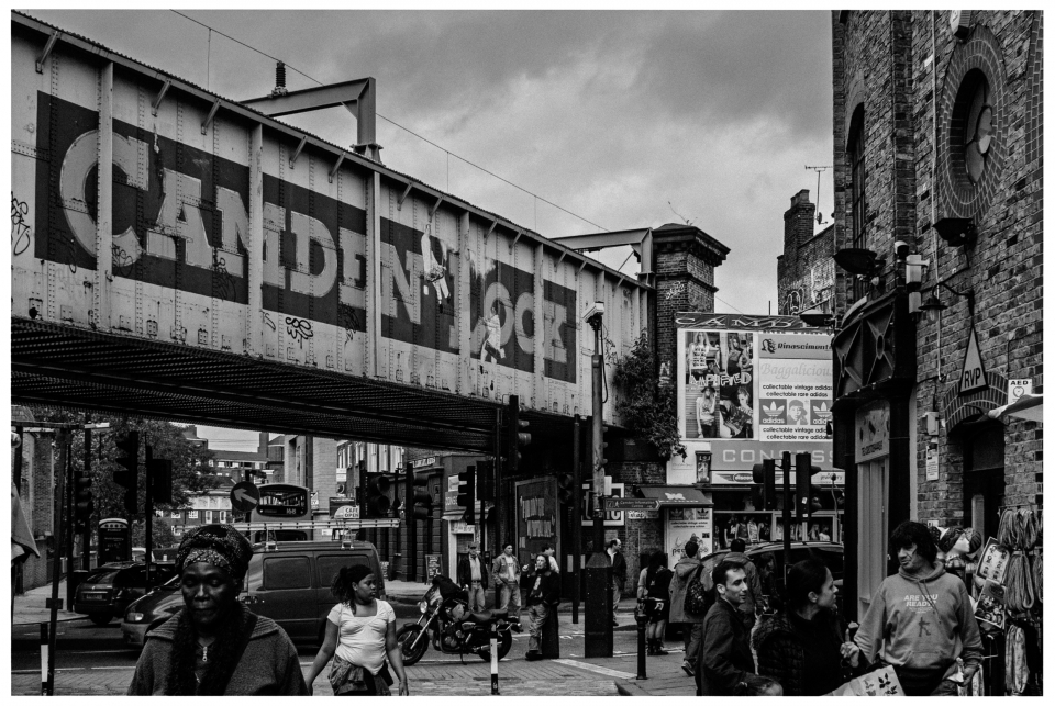 Belebte Straße unter "CAMDEN LOCK"-Brücke, Menschen, Geschäfte, Werbetafeln in Schwarz-Weiß, © Klaus Gruber | Fotograf Fürth