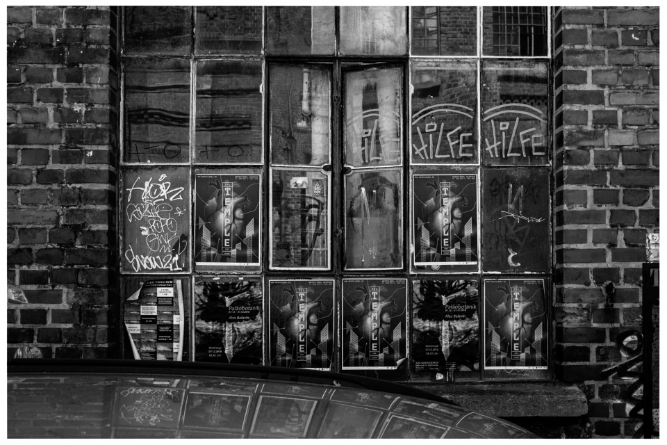 Backsteinmauer mit großen Fenstern, vielen Postern, Graffiti und Spiegelung von Gebäuden, © Klaus Gruber | Fotograf Fürth