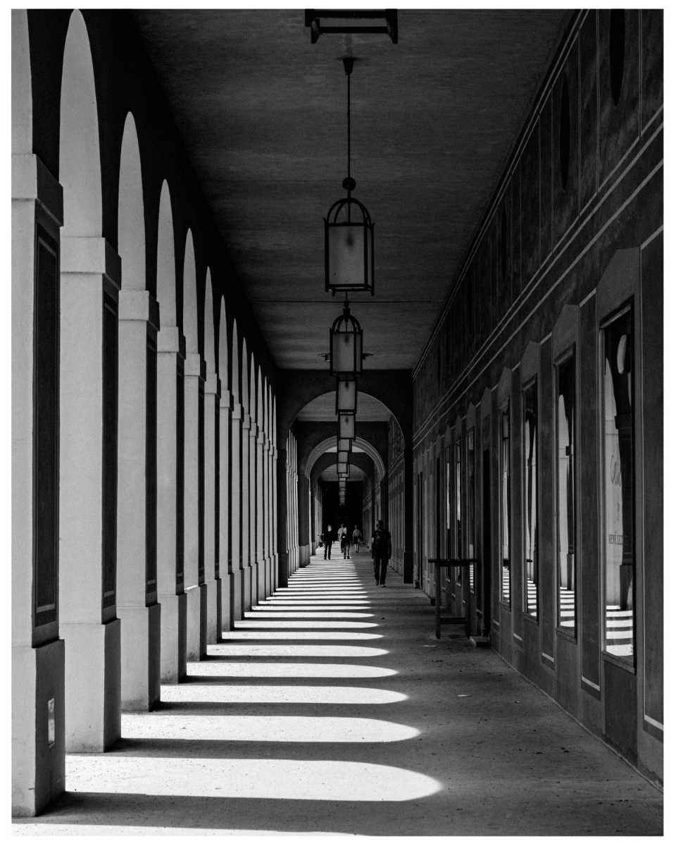 Überdachter Gehweg mit Bögen, Fenstern und Hängelampen; Personen in der Ferne sichtbar, © Klaus Gruber | Fotograf Fürth