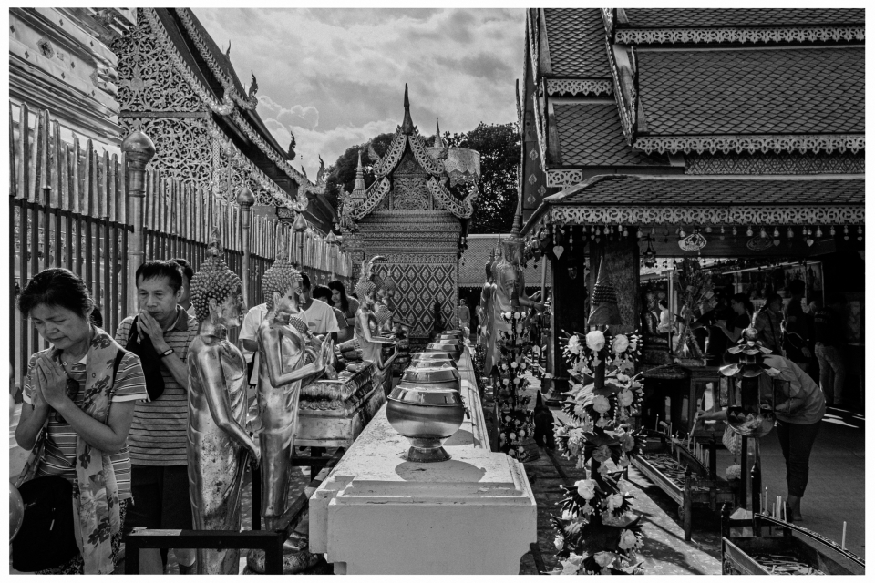 Traditioneller thailändischer Tempel mit reich verzierten Dächern und betenden Menschen, © Klaus Gruber | Fotograf Fürth