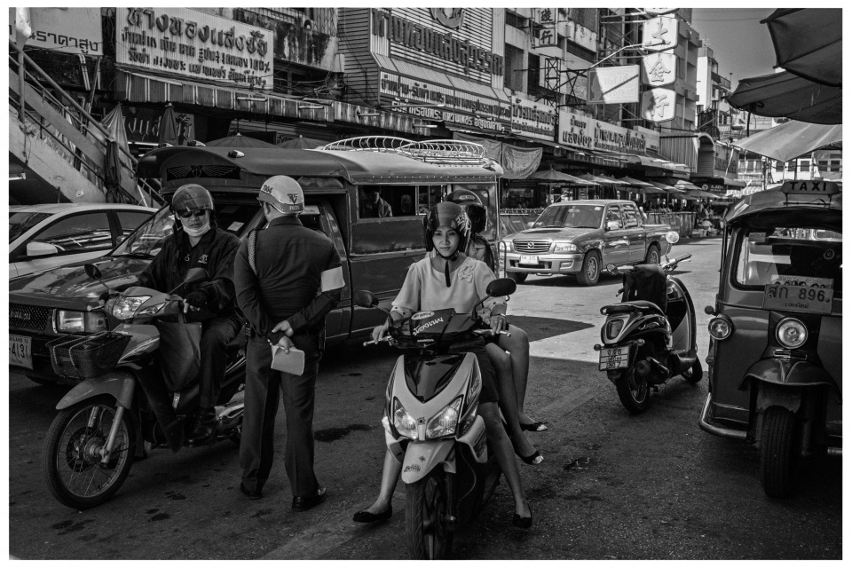 Städtische Szene mit Motorrädern, Verkehrspolizist, Autos, Tuk-Tuk und Straßenschildern, © Klaus Gruber | Fotograf Fürth