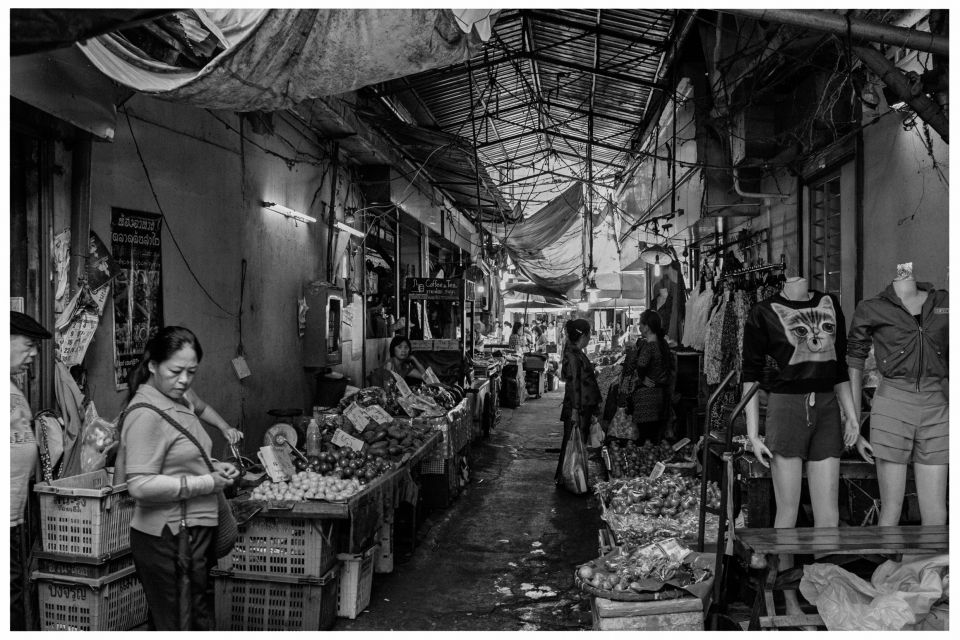 Überdachter Marktgang mit Obst, Gemüse und Kleidung, Menschen bewegen sich durch den Bereich, © Klaus Gruber | Fotograf Fürth