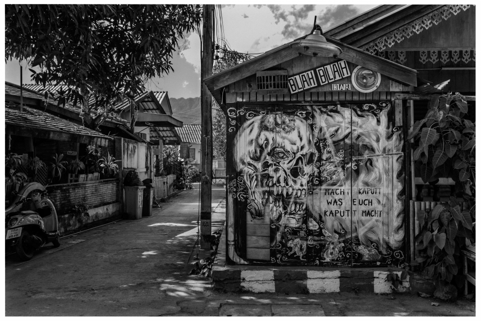 Schwarz-weiße Gasse mit bemalter Hauswand, Skelettmotiv und Schriftzug, angrenzender Motorroller, © Klaus Gruber | Fotograf Fürth